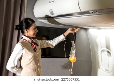Flight attendant woman in airline uniform demonstrate how to use oxygen equipment to passengers on board - Shutterstock ID 2275057551