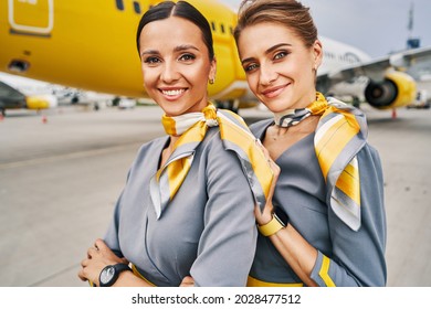 Flight Attendants Dressed In Stylish Uniforms Standing At The Airport