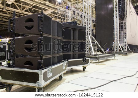 Flight cases with line array speakers. Stage, trusses, led screen and sound speakers background. Installation of professional concert equipment.