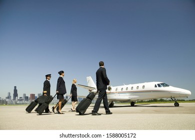 Flight crew wheeling suitcases to airplane on tarmac - Shutterstock ID 1588005172