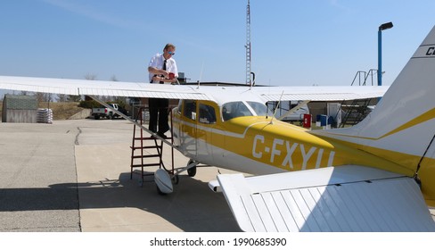 Flight instructor pilot filling yellow and white Cessna 172 airplane with jet fuel on a sunny day