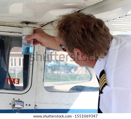Flight instructor in uniform doing pre-flight check testing fuel before lesson - safety first concept