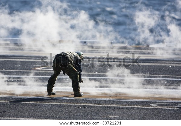 Flight\
line crewman checks the catapult tracks in-between launches aboard\
a US aircraft carrier.\
\
\
\
This photo is represented on my\
website:\
http://www.artistovision.com/military/carrier-crewman.html
