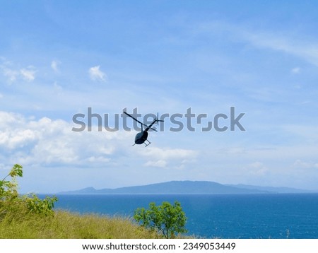 Flight over the sea. Small helicopter in the sky. A black private helicopter flies over the sea next to a tropical island.                               