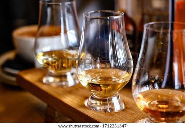 Flight of Scottish whisky, tasting glasses with\
variety of single malts or blended whiskey spirits on distillery\
tour in Scotland, UK