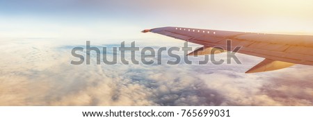 Flight wing panorama with copy space. Aircraft wing above the earth and clouds. Flight in sky. Travel by airlines for vacations.