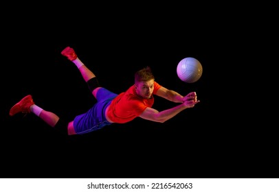 Flight. Young man, professional volleyball player in sports uniform in jump with ball isolated on dark background. Sportive man playing volleyball. Action, sport, health, team, fitness concept - Powered by Shutterstock