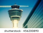 Flights management air control tower and passenger terminal in Munich international airport with flying plane in clear sky. Stock photo with split toning effect.