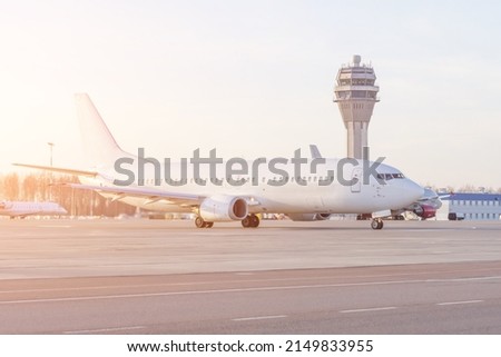 Flights management air control tower and passenger terminal in International airport with flying plane in clear sky, with split toning effect