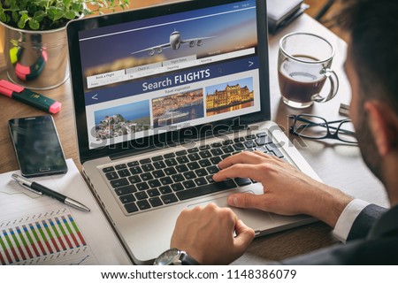 Flights online booking and reservation. Man working with a computer, search flights on the screen, office business background.