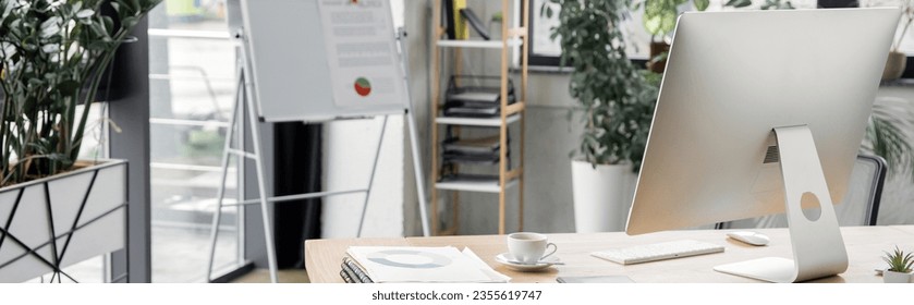 flip chart, work desk with computer monitor, documents and coffee cup, modern office, banner