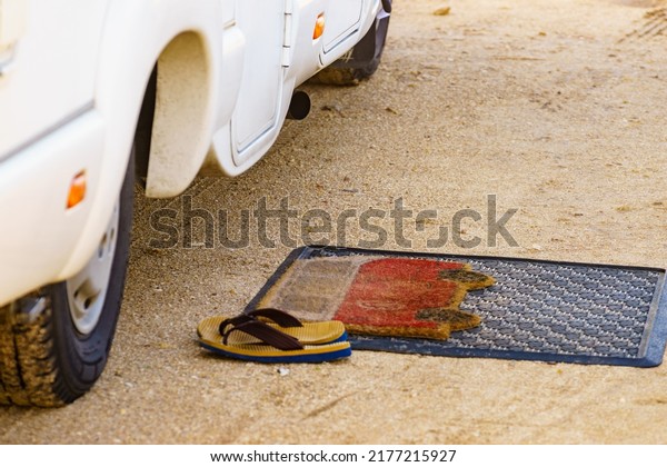 Flip flops on doormat in front of camper car.\
Travel in motorhome,\
holidays.
