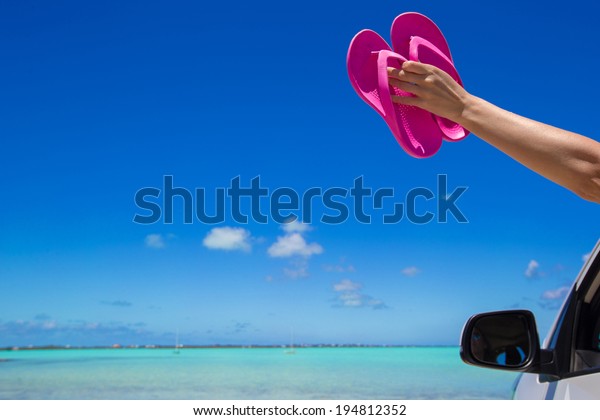 Flip Flops from the window of a car on background\
tropical beach