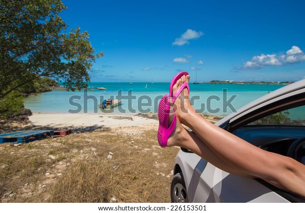 Flip Flops from the window of a car on background\
tropical beach