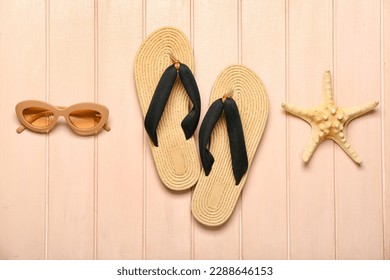 Flip-flops with sunglasses and starfish on beige wooden background
