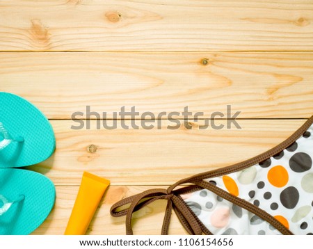 Flip-flops, women's bikini bottoms and sunscreen for protecting skin from the sun on wooden background. Women's beachwear accessories with copy space. Summer holiday concept.
