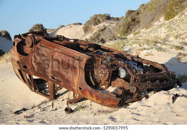 A flipped\
abandoned car found near a beach.\
