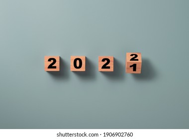 Flipping wooden block cube to change 2021 to 2022 on blue background, Merry Christmas and happy new year preparation concept.
