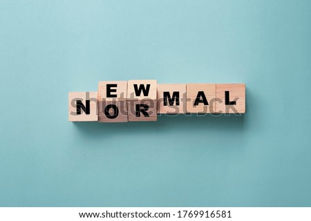 Flipping wooden block cubes for new normal wording on green background. The world is changing to balance it into new normal include business , economy , environment and health.