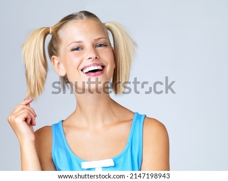 Flirtatious moves. Portrait of attractive young blonde in pigtails playing with her hair.