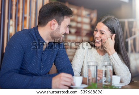 Flirting in a cafe. Beautiful loving couple sitting in a cafe enjoying in coffee and conversation. Love and romance. 