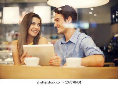 Flirting couple in cafe using digital tablet - Powered by Shutterstock