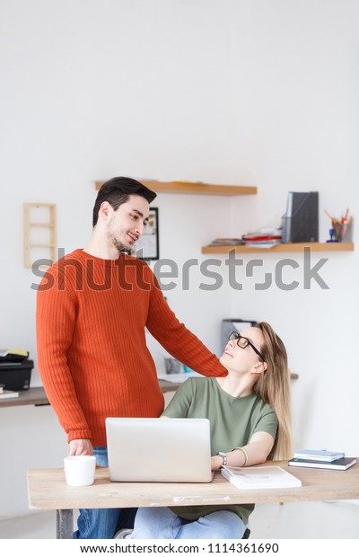 Flirting at work. Employees of an office or
a printing house - charming woman and handsome man flipping through
a book sitting at a table with
computer
