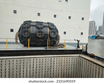 Float A large black float sits on top of the deck. Surrounded by chains and old tires. Used for balancing ships while moored in port or in the middle of the sea and maritime transport concept.