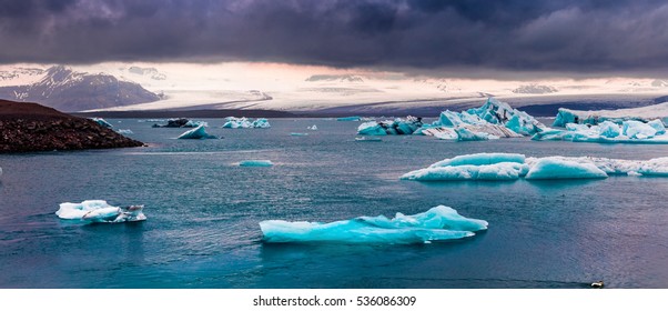 Floating Of Blue Icebergs In Jokulsarlon Glacial Lagoon. Colorful Sunset Panorama In Vatnajokull National Park, Southeast Iceland, Europe. Artistic Style Post Processed Photo.