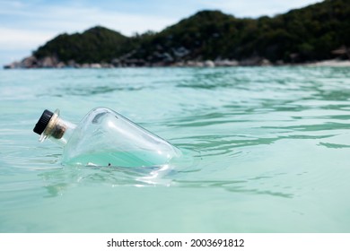 Floating Bottle In The Sea With Island Background.