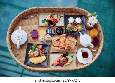 Floating breakfast tray in luxury pool hotel. Healthy set of dishes served in tropical resort. Relaxing, Exotic summer travel, holiday, vacation and weekend. Top view