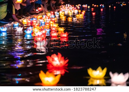 Floating colored lanterns and garlands on river at night on Vesak day for celebrating Buddha's birthday in Eastern culture, that made from paper and candle