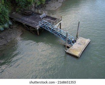 Floating concrete jetty with metal bridge and wooden piles. Aerial view. Stock photo.