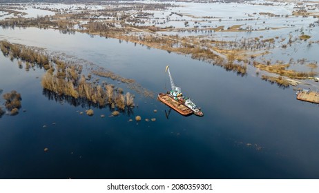 Floating crane on the river. Dredging crane working near shore. Conservation river flow. Nature, river, sky, clouds. Cleaning the bottom of the river.