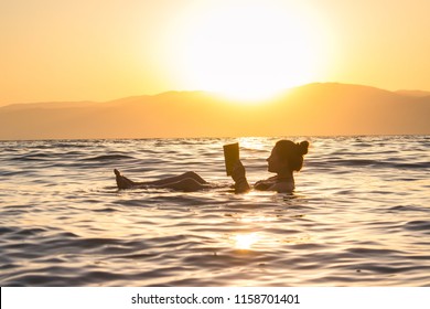 Floating In The Dead Sea Sunset, Israel