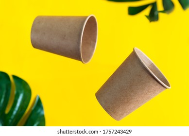 Floating Eco Friendly Paper Disposable Mockup Cups Above Yellow Background With Green Palm Leaves. Zero Waste