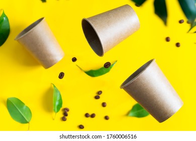 Floating eco friendly paper disposable mockup cups above yellow background with green palm leaves. Zero waste