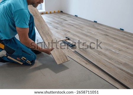 Floating floor work. The worker hold the board of vinyl plank before insert to the floor click system. 