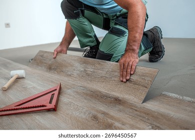 Floating floor work. The worker inserts the board of vinyl plank to the click system of Floating floor. 