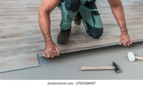 Floating floor work. The worker inserts the board of vinyl plank to the click system of Floating floor. 