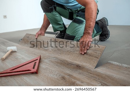 Floating floor work. The worker inserts the board of vinyl plank to the click system of Floating floor. 