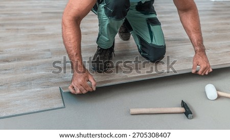 Floating floor work. The worker inserts the board of vinyl plank to the click system of Floating floor. 