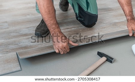Floating floor work. The worker inserts the board of vinyl plank to the click system of Floating floor. 
