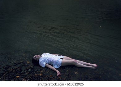 Floating girl lying on the rock of dark river . Ophelia conceptual