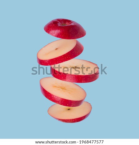 Floating levitating ripe apple on a blue background. Vitamins, healthy diet concept. Minimal fruit idea. Sliced apple floating in the air. Creative concept with flying fruits.