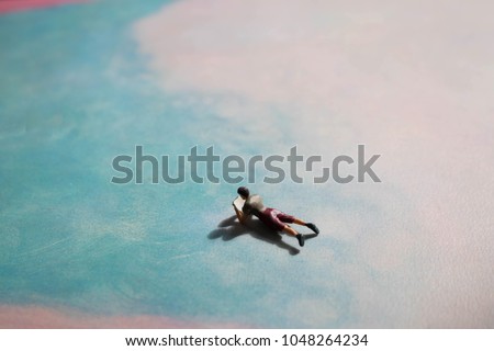 Floating miniature person reading on cloud or sky like background. Fantasy or fairy tale escape into a magical land of books. Passion or love for literature and literacy. Reader of ebooks or paperback