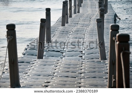 Floating plastic pontoon with handle pole on the beach in blue sky,Plastic floating pier with protection fence in the sea.An anchored raft-like platform,Detail of Plastic floating walk way.