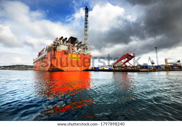Floating, production, storage and offloading FPSO\
vessel moored to the shore in a port, close-up. Riga, Latvia. Fuel\
and power generation, industry, global communications,\
environmental damage