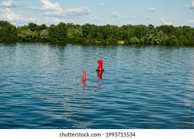 Floating red navigational buoy on blue water of Dnipro River. Buoy in the river. Navigation equipment. Tranquil water surface.