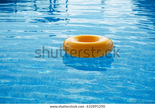 floating ring on blue water swimpool with waves\
reflecting in the summer\
sun